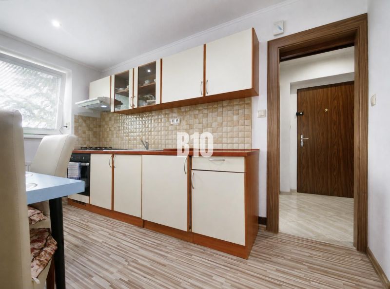 Küche mit Holzboden in einer 3-Zimmer-Wohnung, ausgestattet mit hellen Möbeln.