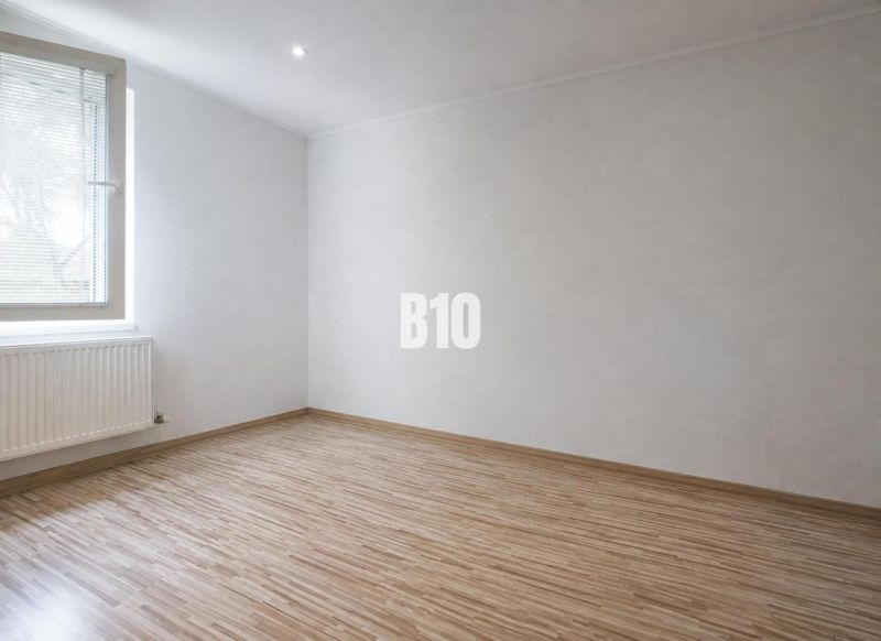 Ein Zimmer in einer 3-Zimmer-Wohnung mit einem Boden in Holzoptik und weißen Wänden.