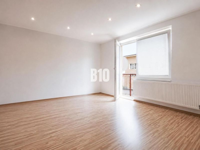 Ein geräumiges Zimmer in einer 3-Zimmer-Wohnung mit einem Holzboden und einem großen Fenster.