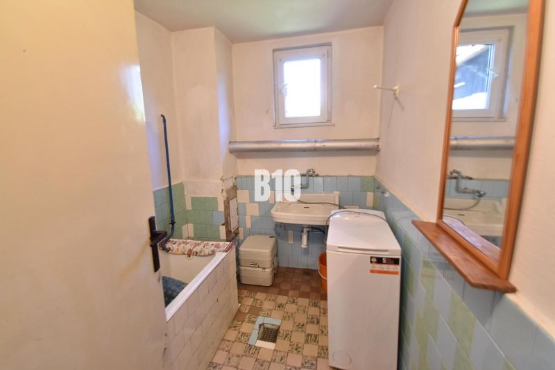 Ein Badezimmer in einem Einfamilienhaus mit Waschmaschine, Badewanne und Waschbecken, gefliest mit bunten Fliesen.