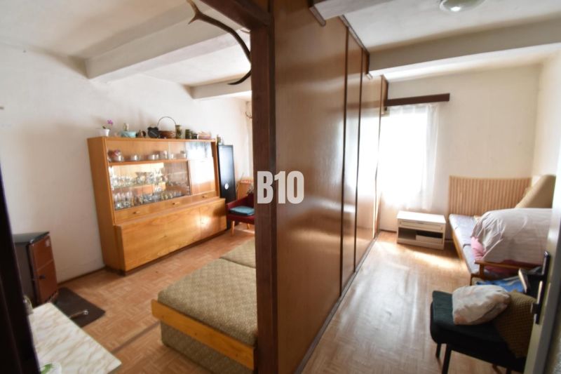 Wohnzimmer in einem Einfamilienhaus mit Möbeln und Boden in Holzoptik.