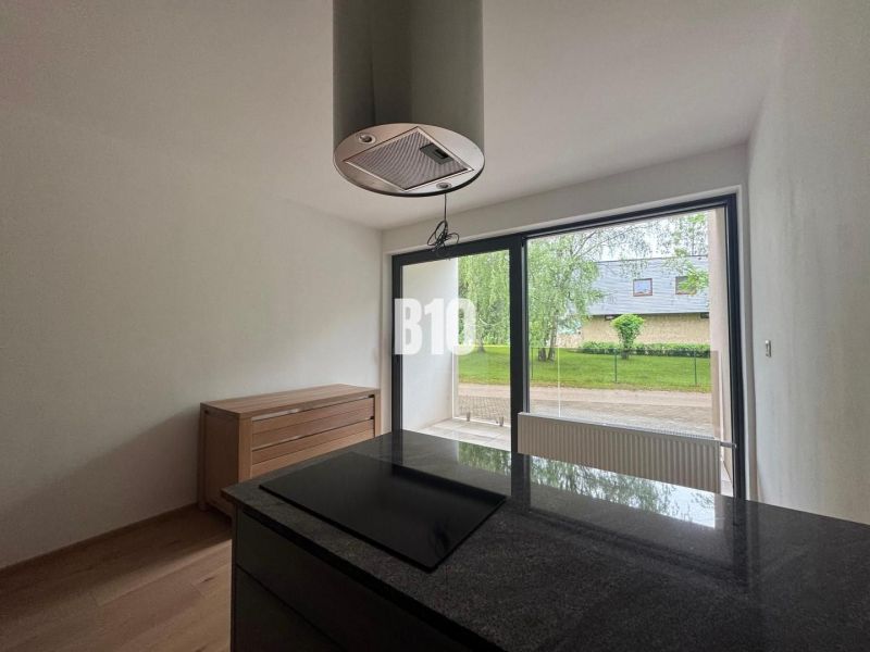 Küche in einer 2-Zimmer-Wohnung mit Holzboden und großen Fenstern.