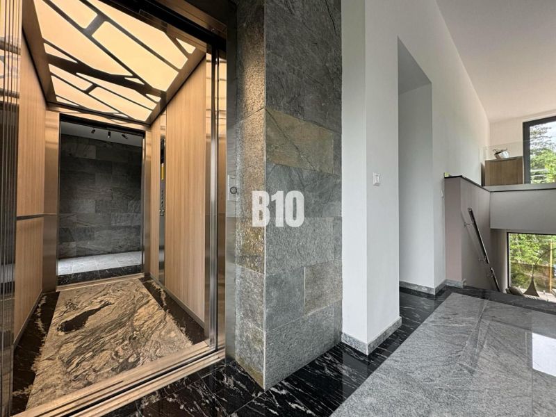Der Flur mit stilvollem Aufzug in einer 2-Zimmer-Wohnung, mit Steinwänden und Steinboden.