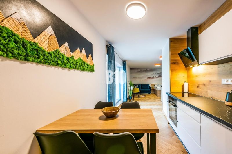 Innenraum einer Ferienwohnung mit Küchenzeile und Tisch, Boden mit Holzdekor.