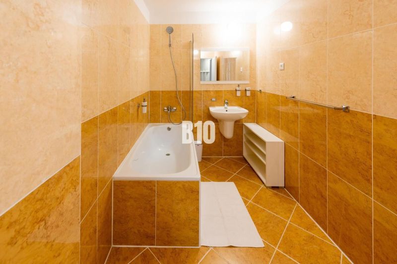 Badezimmer in einer Ferienwohnung mit Badewanne, Waschbecken und hellen Fliesen.