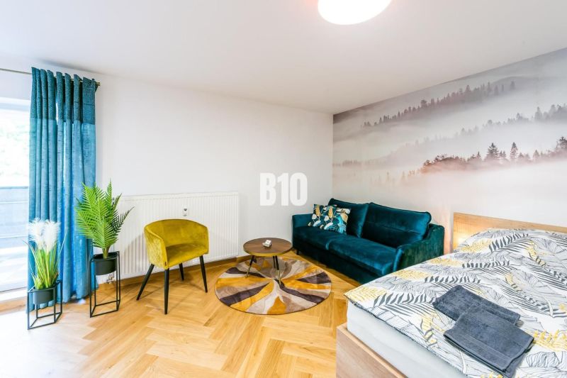 Stilvolles Ferienapartment mit Holzboden, Sofa und Pflanzen.