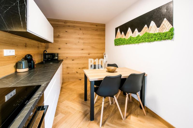 Innenraum einer Ferienwohnung mit Küche, Esstisch und Boden in Holzoptik.