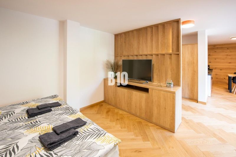 Ferienwohnung mit Bett, Fernseher, Holzboden und Holzmöbeln.