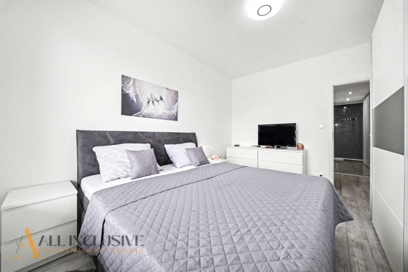 Schlafzimmer in einer 3-Zimmer-Wohnung mit Doppelbett, Fernseher und Holzboden.