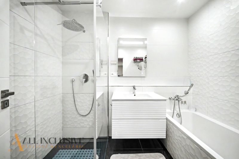 Badezimmer mit moderner Duschkabine und Badewanne in einer 3-Zimmer-Wohnung mit weißen Fliesen.