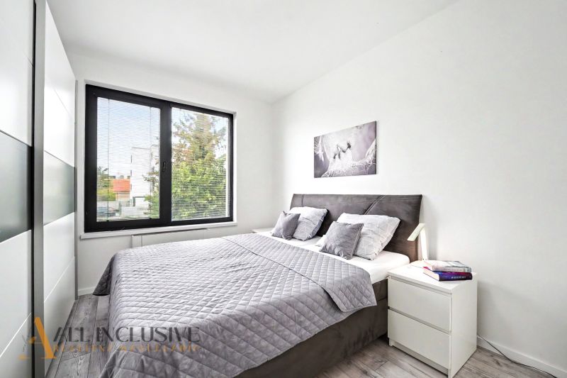 Schlafzimmer in einer 3-Zimmer-Wohnung mit Holzboden, großem Bett und Bild an der Wand.