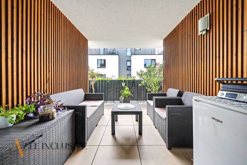 Möblierte Terrasse einer 3-Zimmer-Wohnung mit Rattanmöbeln und Blumendekoration.