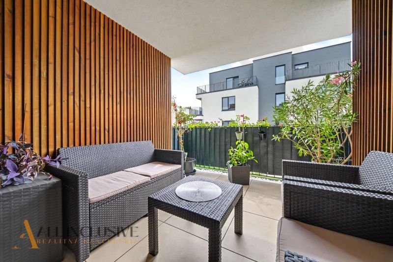 Balkon einer 3-Zimmer-Wohnung mit Rattanmöbeln und Pflanzen.