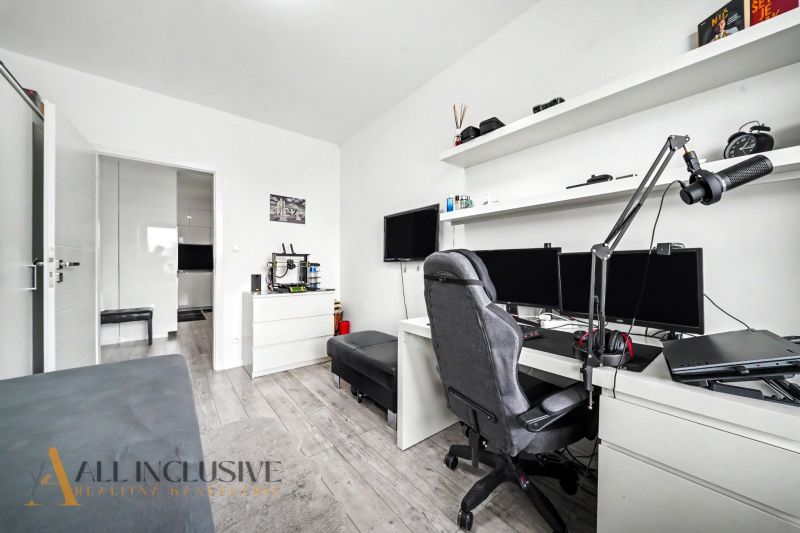 Ein Arbeitszimmer mit Computer, Regalen und einem Boden in Holzoptik in einer 3-Zimmer-Wohnung.