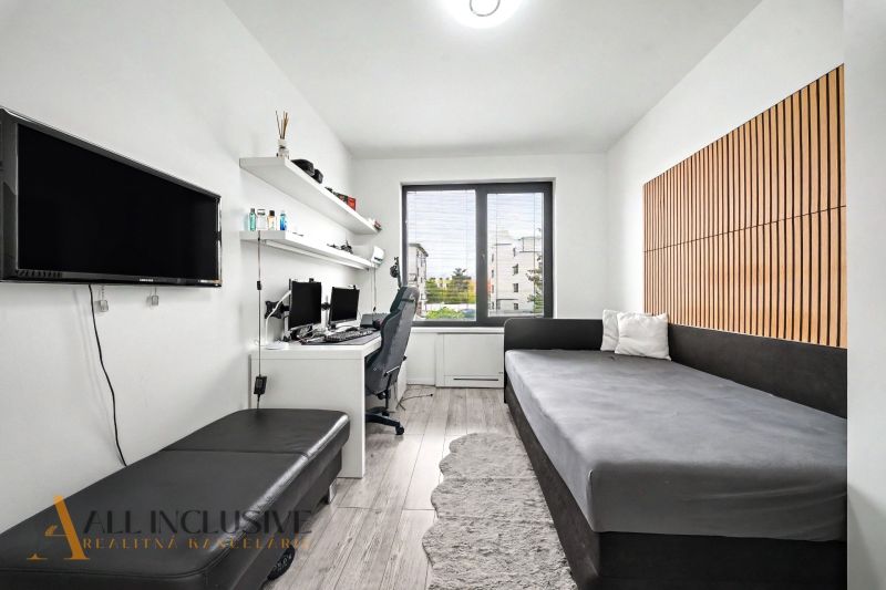 Ein Zimmer in einer 3-Zimmer-Wohnung mit einem Schreibtisch, einem Sofa und einem Boden in Holzoptik.