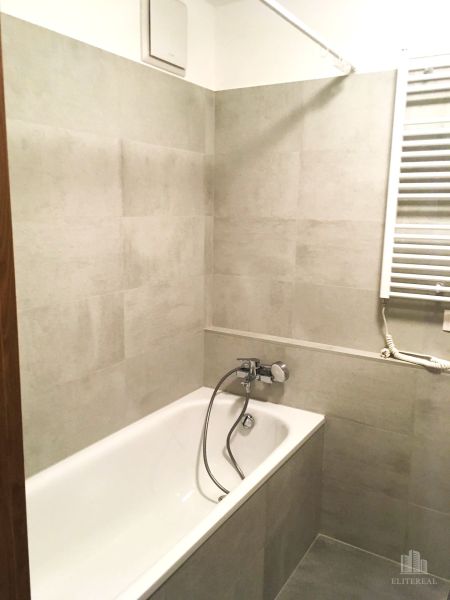 Badezimmer mit Badewanne und hellen Fliesen in einer 2-Zimmer-Wohnung.