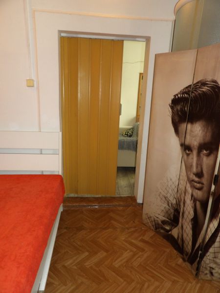 Ein Zimmer in einer 2-Zimmer-Wohnung mit einem Bett, einem Boden in Holzoptik und Schiebetüren.