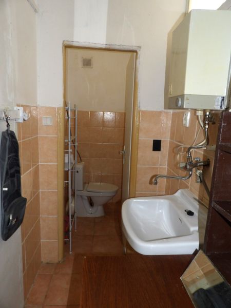 Badezimmer einer Zweizimmerwohnung mit Toilette und Waschbecken im einfachen Stil.