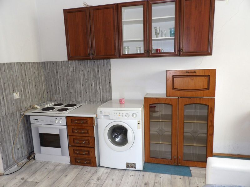 Küche in einer 2-Zimmer-Wohnung mit Elektroherd, Waschmaschine und Boden in Holzoptik.
