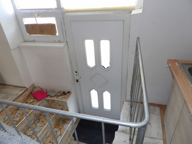 Treppen und Eingangstür in einer 2-Zimmer-Wohnung mit Geländer und Mosaikfliesen.