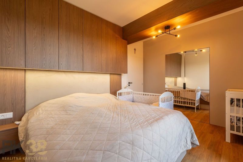 Schlafzimmer in einer 2-Zimmer-Wohnung mit Kinderbett und Holzboden.