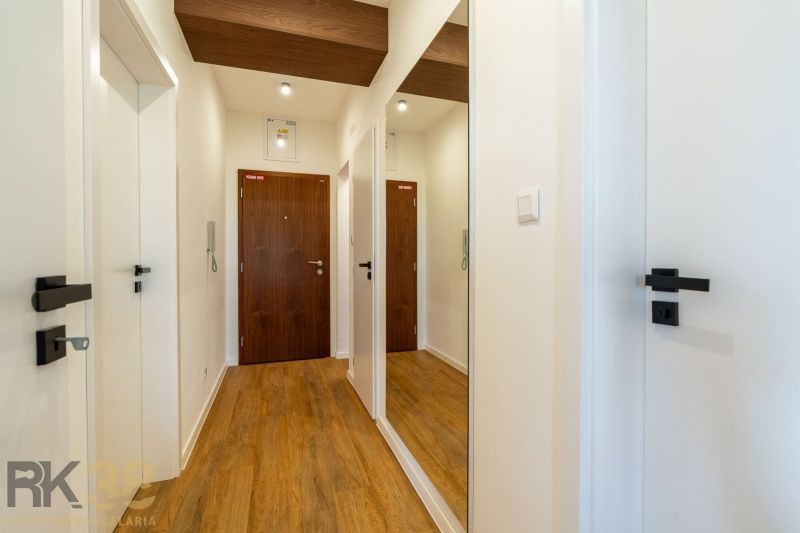 Der Flur in der 2-Zimmer-Wohnung mit einem Boden in Holzoptik und einem Spiegel an der Wand.
