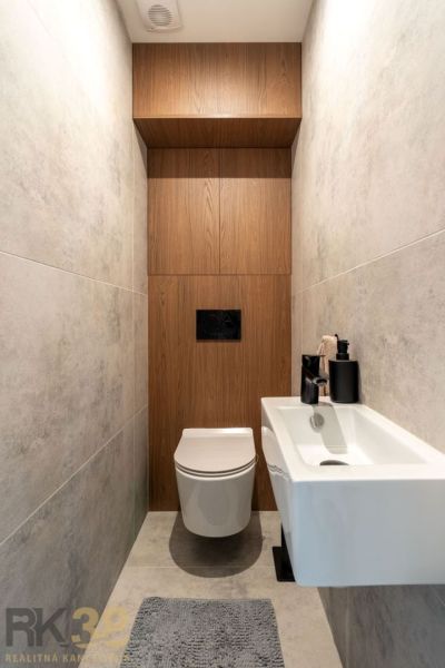 Ein Badezimmer mit einem Boden in Holzoptik und einer weißen hängenden Toilette in einer Zweizimmerwohnung.