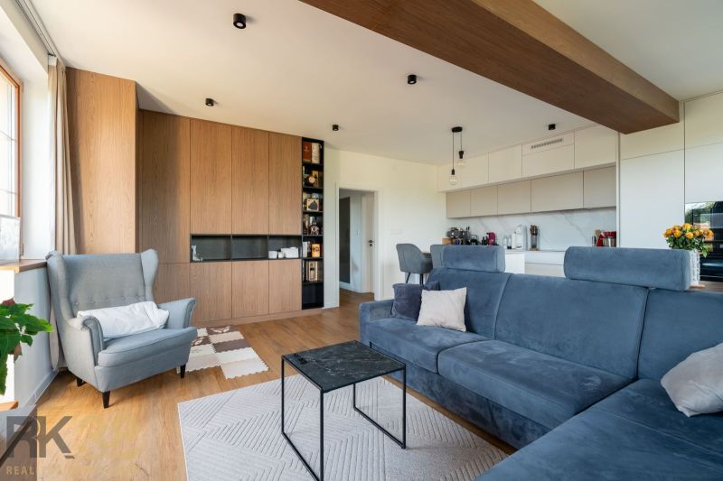 Wohnzimmer einer Zweizimmerwohnung mit Holzboden, blauem Sofa und Sessel.