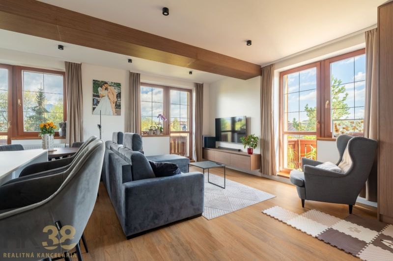 Wohnzimmer in einer Zweizimmerwohnung mit Sofa, Fernseher und Holzboden.