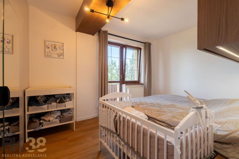 Schlafzimmer in einer 2-Zimmer-Wohnung mit Kinderbett und Holzboden.