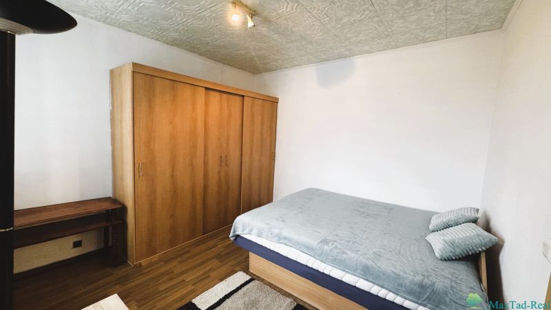 Schlafzimmer in einer 4-Zimmer-Wohnung mit Bett, Schrank und Boden mit Holzdekor.