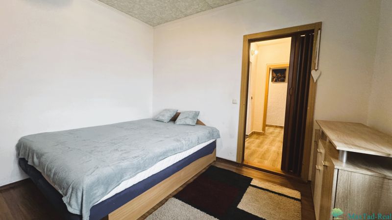 Schlafzimmer in einer 4-Zimmer-Wohnung mit Bett, Teppich und Möbeln in Holzoptik.