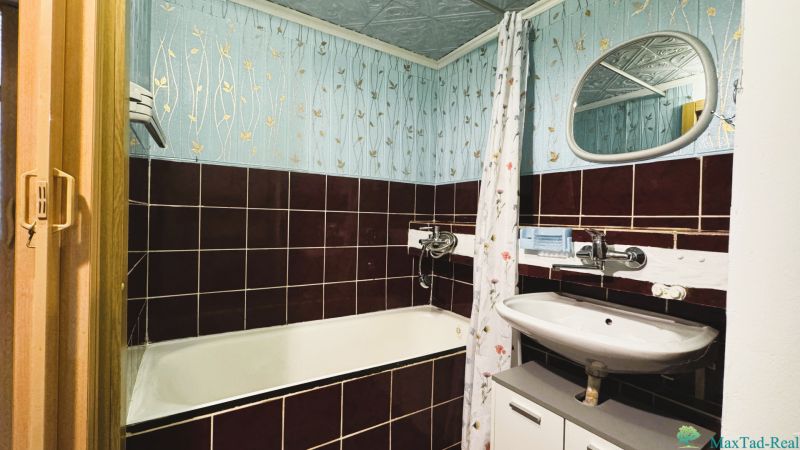 Badezimmer mit einer emaillierten Badewanne und gefliesten Wänden in einer 4-Zimmer-Wohnung.