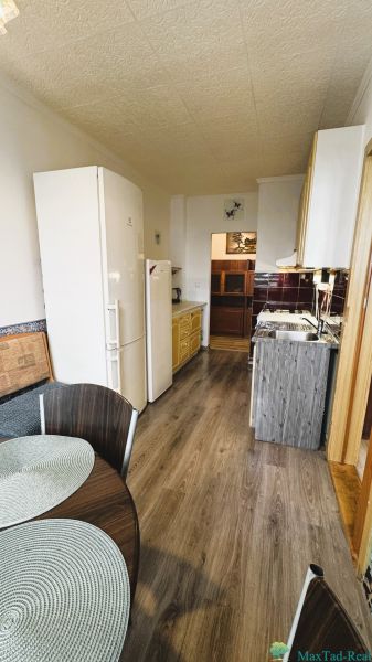 Küche in einer 4-Zimmer-Wohnung mit Holzboden, Esstisch und Geräten.
