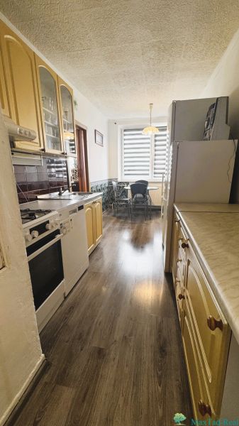 Küche in einer 4-Zimmer-Wohnung mit Küchenzeile und Boden in Holzoptik.
