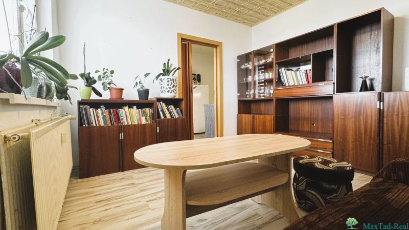 Wohnzimmer mit Schränken, Büchern, Blumen und einem Boden mit Holzdekor in einer 4-Zimmer-Wohnung.