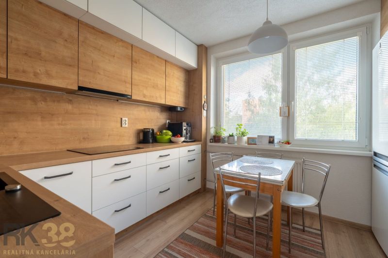 Küche mit Holzboden in einer 3-Zimmer-Wohnung, mit Esstisch am Fenster.