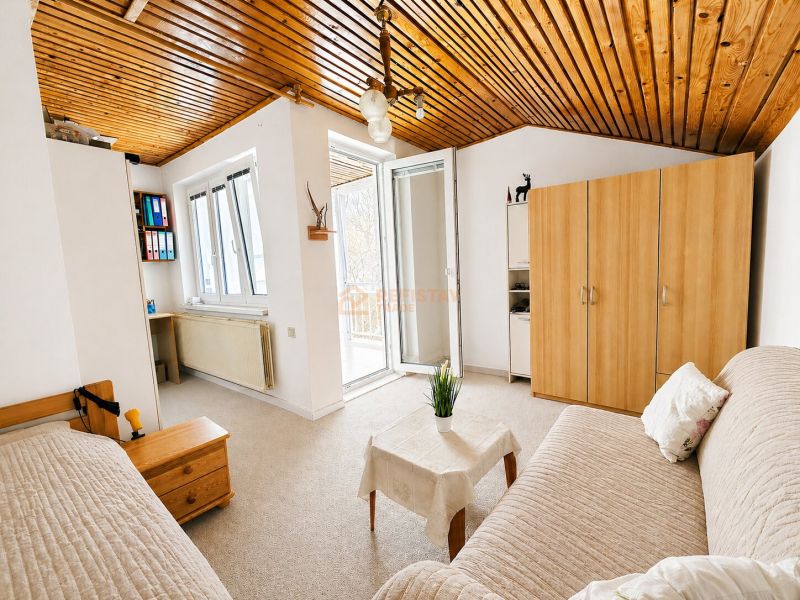 Ein helles Zimmer in einem Einfamilienhaus mit einer Couchgarnitur und einem Kleiderschrank.