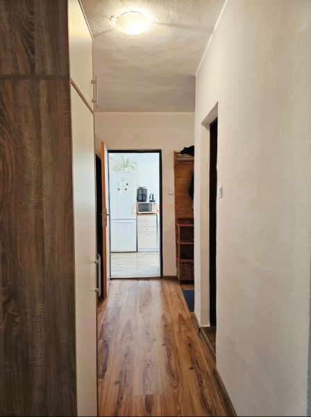 Ein Flur in einem Einfamilienhaus mit einem Boden in Holzoptik und Blick in die Küche.