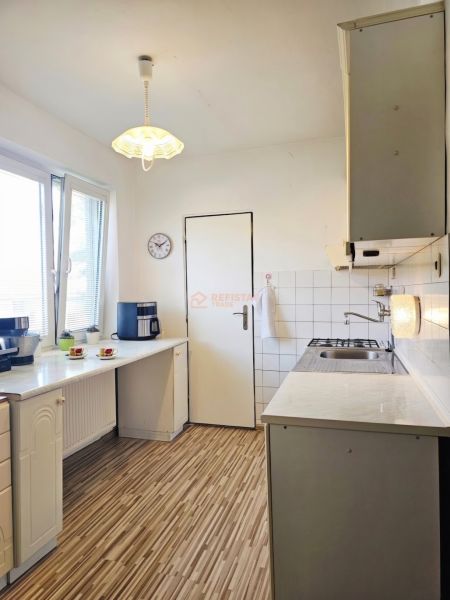 Küche in einem Einfamilienhaus mit Holzboden und weißen Schränken.