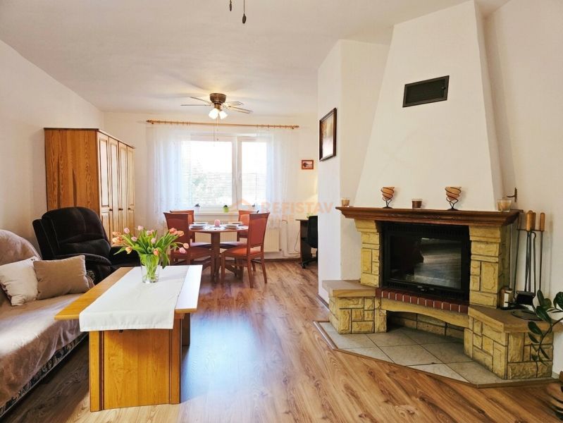 Ein Zimmer eines Einfamilienhauses mit Kamin, Sitzgarnitur und einem Boden mit Holzdekor.