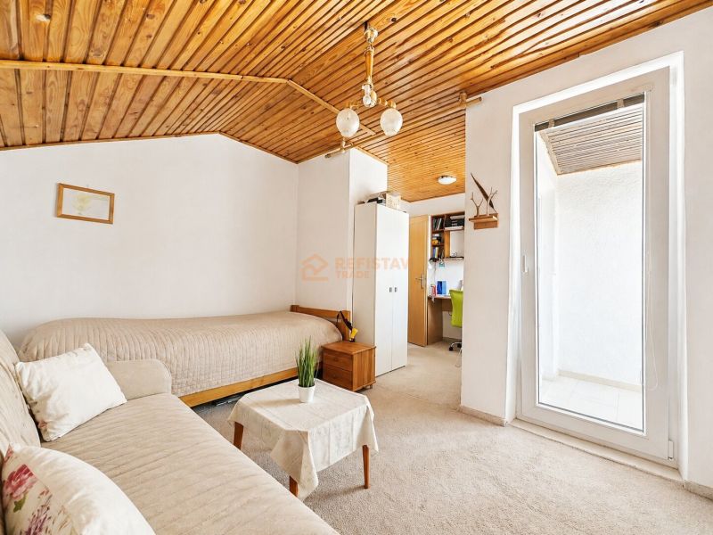 Ein Zimmer in einem Einfamilienhaus mit einer Holzdecke, einem Sofa und einer Arbeitsecke.