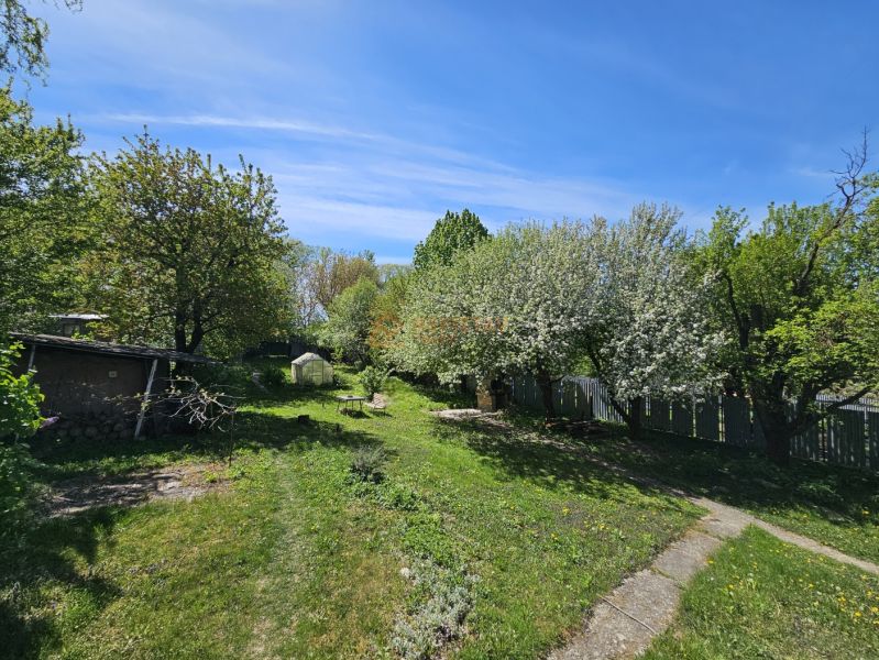 Ein Garten bei einem Einfamilienhaus in Nižná Hutka mit Rasen, Bäumen und einem Pavillon.