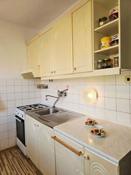 Küche in einem Einfamilienhaus mit weißen Schränken und Theke, Boden mit Holzdekor.