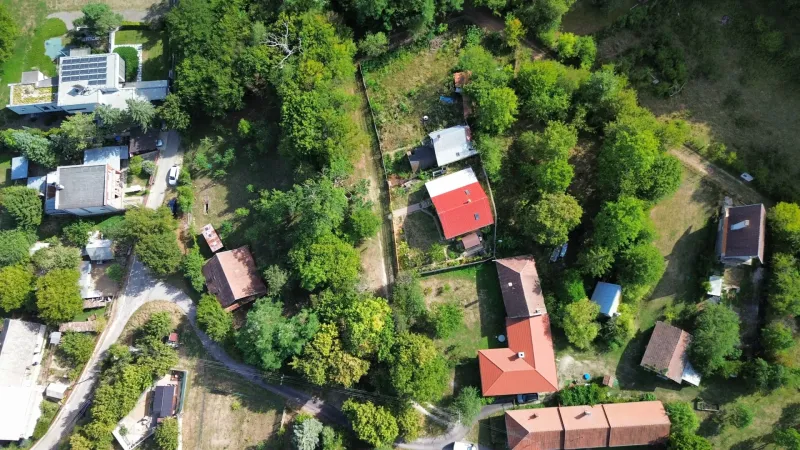 Luftaufnahme von Gärten und Häusern in Kolačno, umgeben von dichtem Grün.