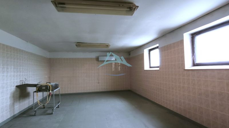 Produktionsräume mit Fliesen, niedriger Decke und Waschbecken.