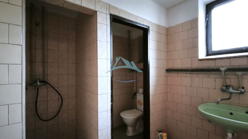 Badezimmer in Produktionsräumen mit Toilette, Waschbecken und Dusche.