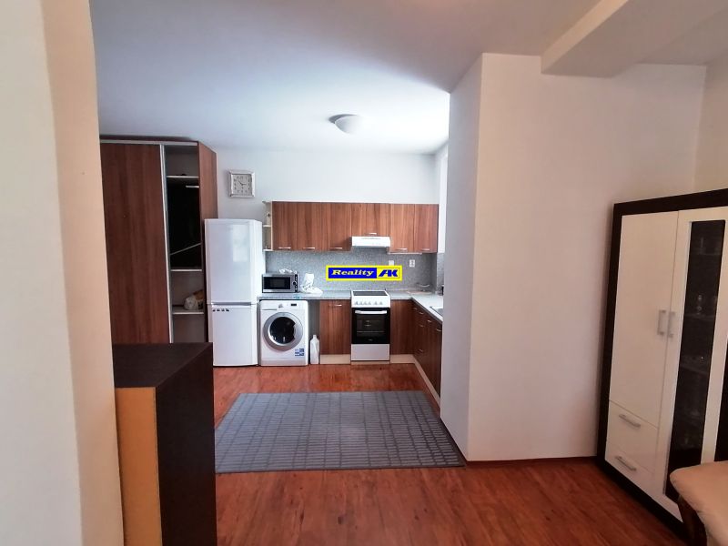 Küche mit Holzboden in einer 2-Zimmer-Wohnung, Geräte, Schränke, Teppich.
