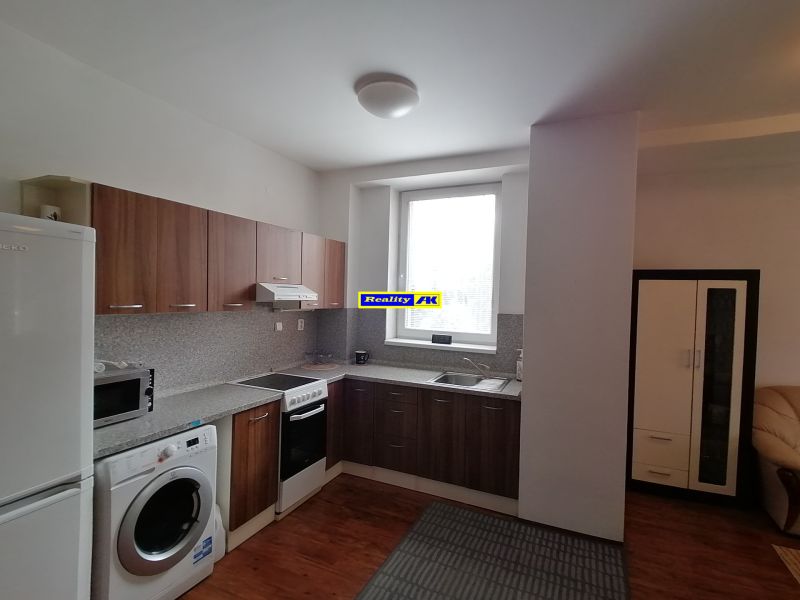 Küche einer 2-Zimmer-Wohnung mit Küchenzeile, Waschmaschine, Kühlschrank und Bodenbelag in Holzoptik.