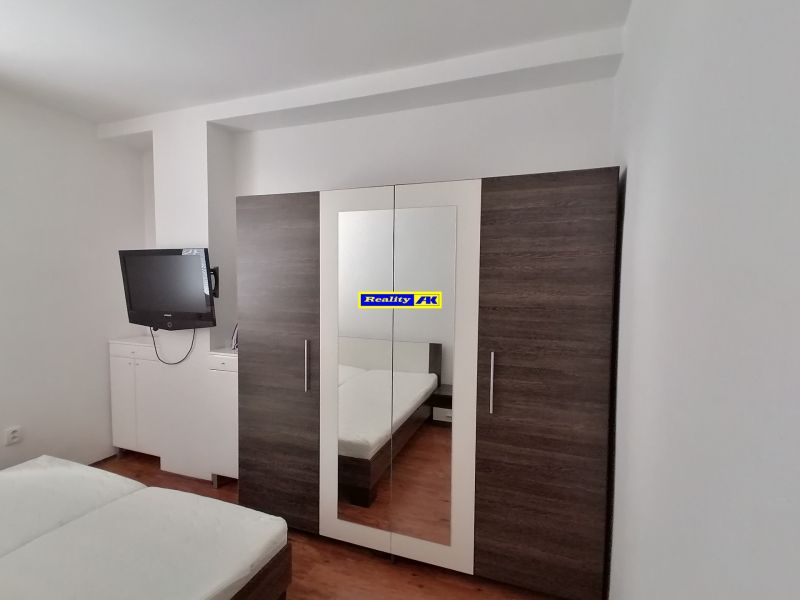 Schlafzimmer mit Fernseher, Kleiderschrank und Bett, 2-Zimmer-Wohnung.